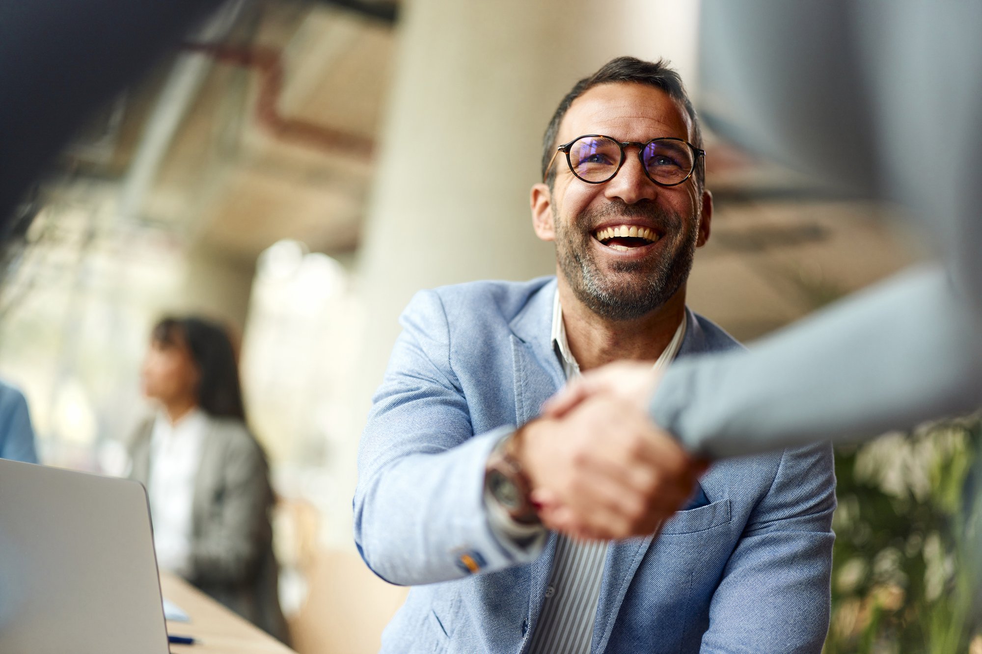 Happy businessman shaking hands with his colleague on a meeting in the office. iStock-2184295789