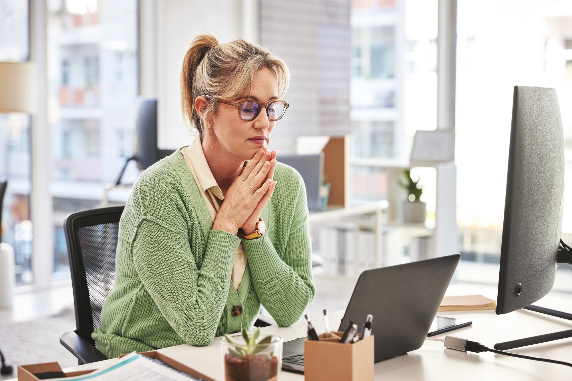 Hero - Eine reife Geschäftsfrau mit Brille, während sie in einem Büro an einem Laptop arbeitet und an einem Schreibtisch sitzt. Geschäftsfrau, die auf ihrem Computer tippt, mit Fokus auf ein Startup iStock-1492592813