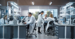 Hero - Three Scientists Discussing Latest Bioengineering Discoveries and Sharing Research Data on Vaccine Efficacy. Diverse Male and Female Colleagues Working in a Modern Medical Research Center iStock-2190227480