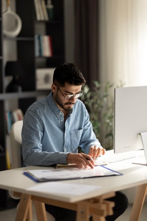 Man working from home. Tisch Laptop. Senkrecht. iStock-1927966993