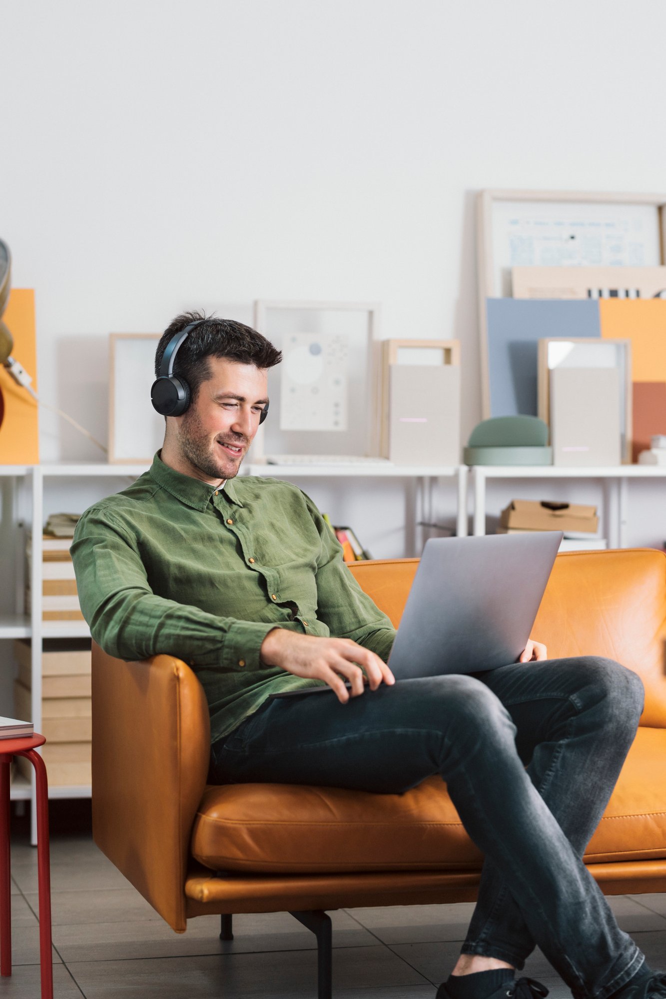 Podcast - ein lächelnder Freelancer, der im Büro sitzt und Kopfhörer aufundhört und Musik hört, während er an seinem Laptop-PC arbeitet iStock-1264090895