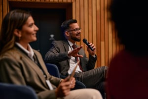 Geschäftsmann spricht während einer Konferenz über das Mikrofon.iStock-2220841396