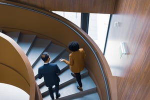 Geschäftskollegen diskutieren über Wendeltreppe iStock-2183159377