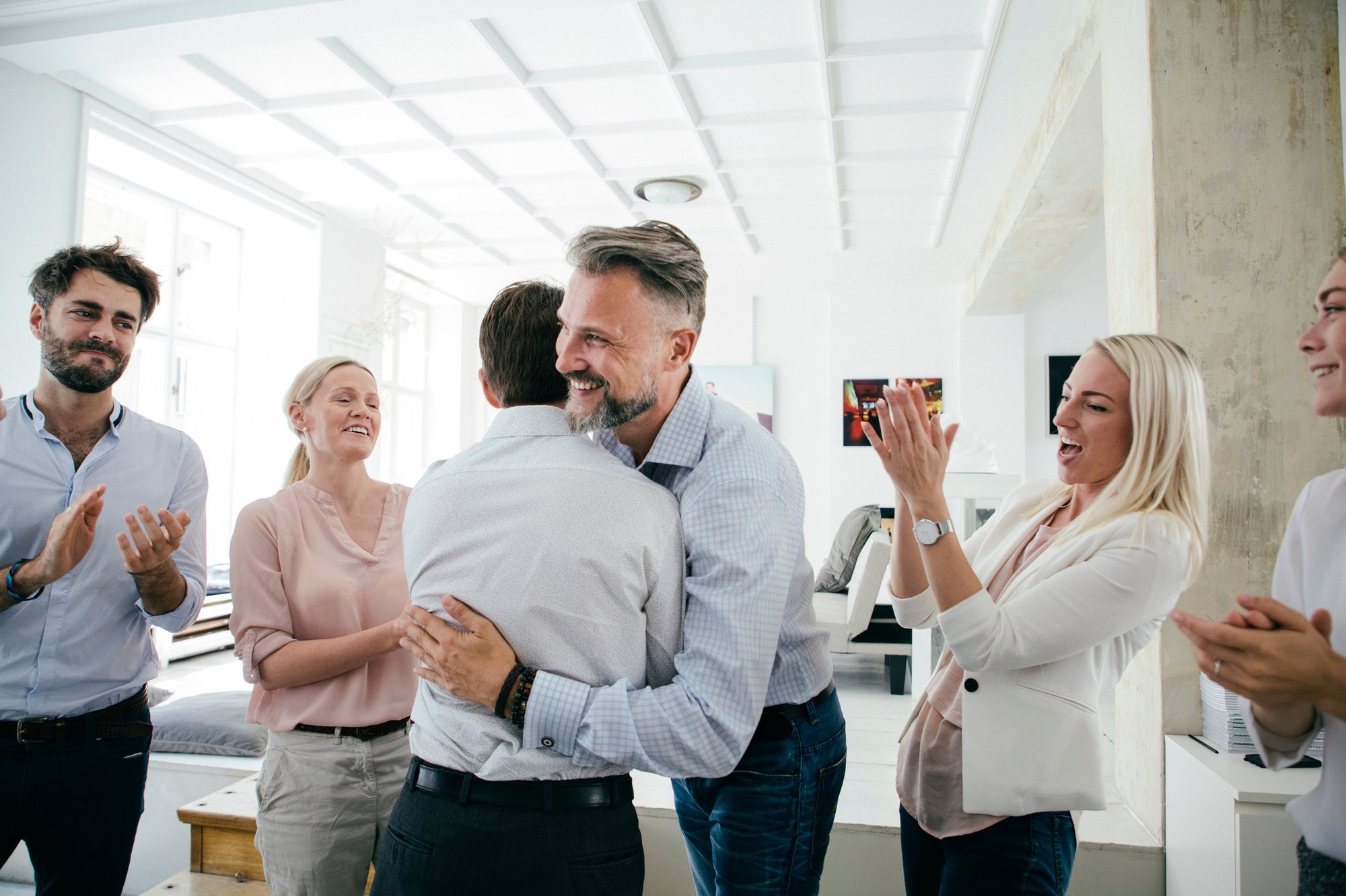 Mann umarmt Kollegen.Feiern im Büro nach erfolgreichen Pitch von Team.iStock-841337566