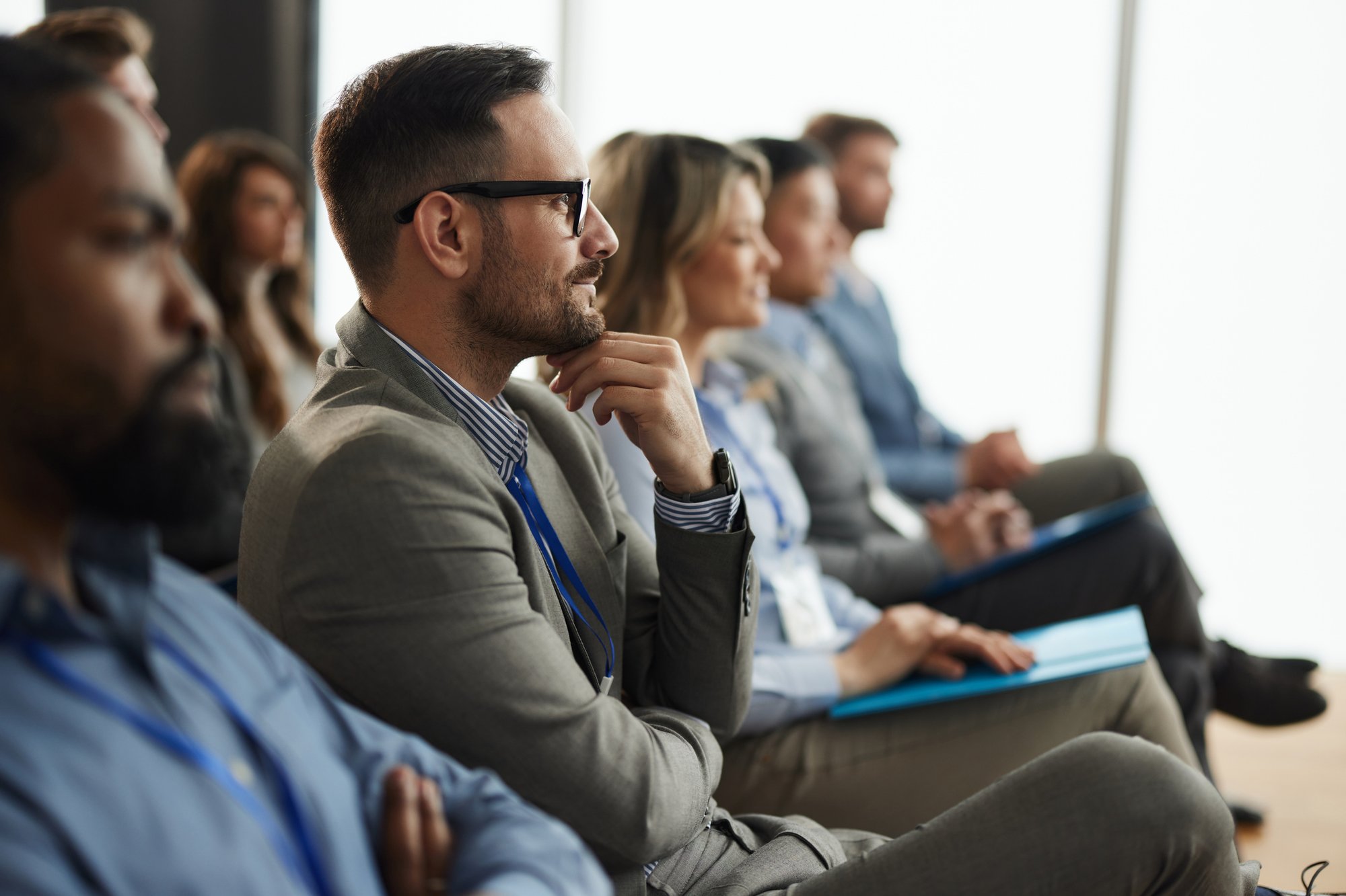 Lächelnder männlicher Unternehmer mit seinen Kollegen auf Bildungsveranstaltung iStock-2158944796