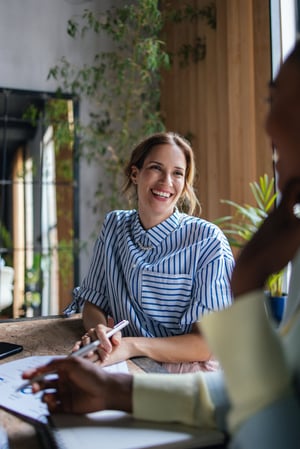 Lächelnden Geschäftsfrau, die am Tisch sitzt iStock-1640698298