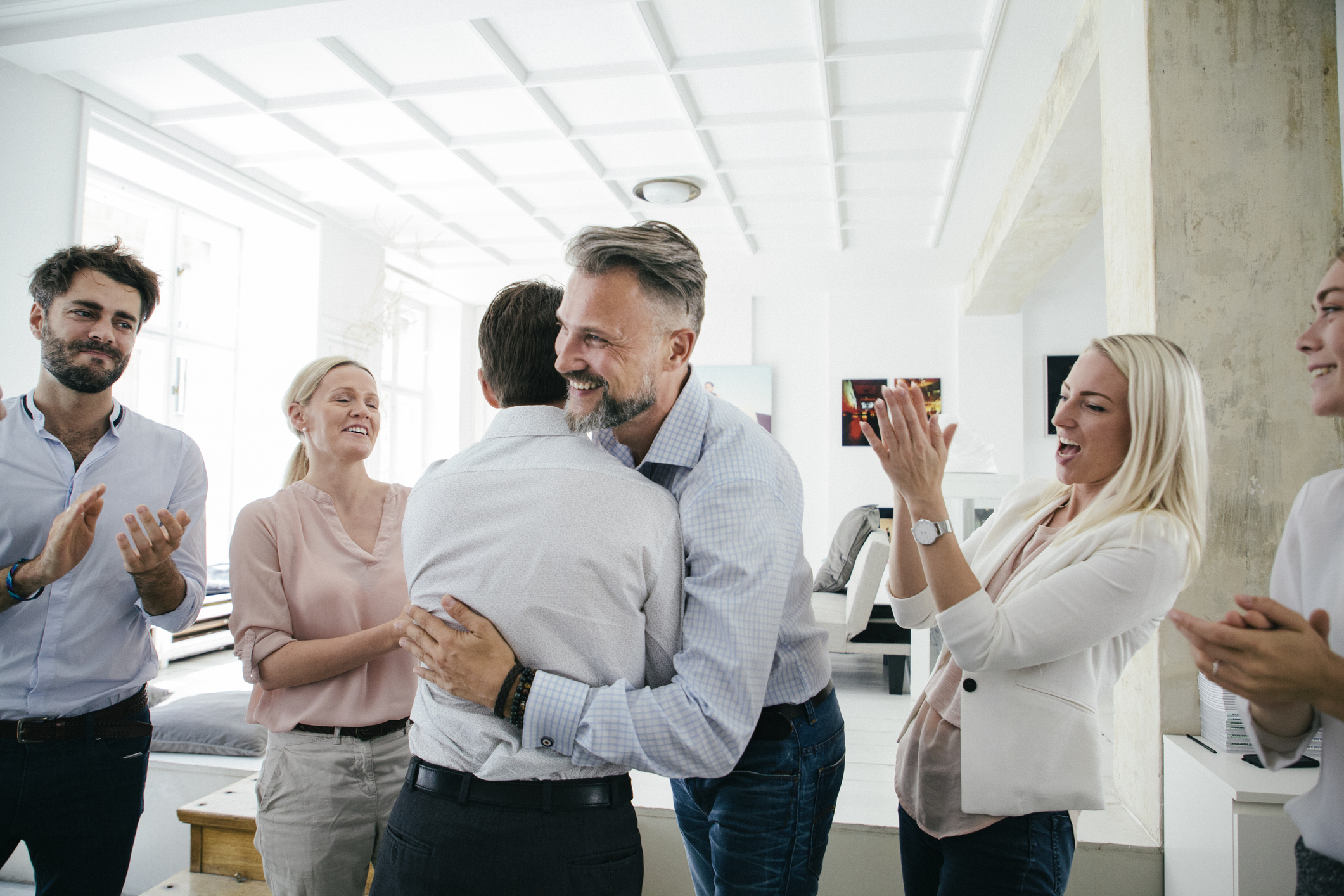Mann umarmt Kollegen.Feiern im Büro nach erfolgreichen Pitch von Team.iStock-841337566