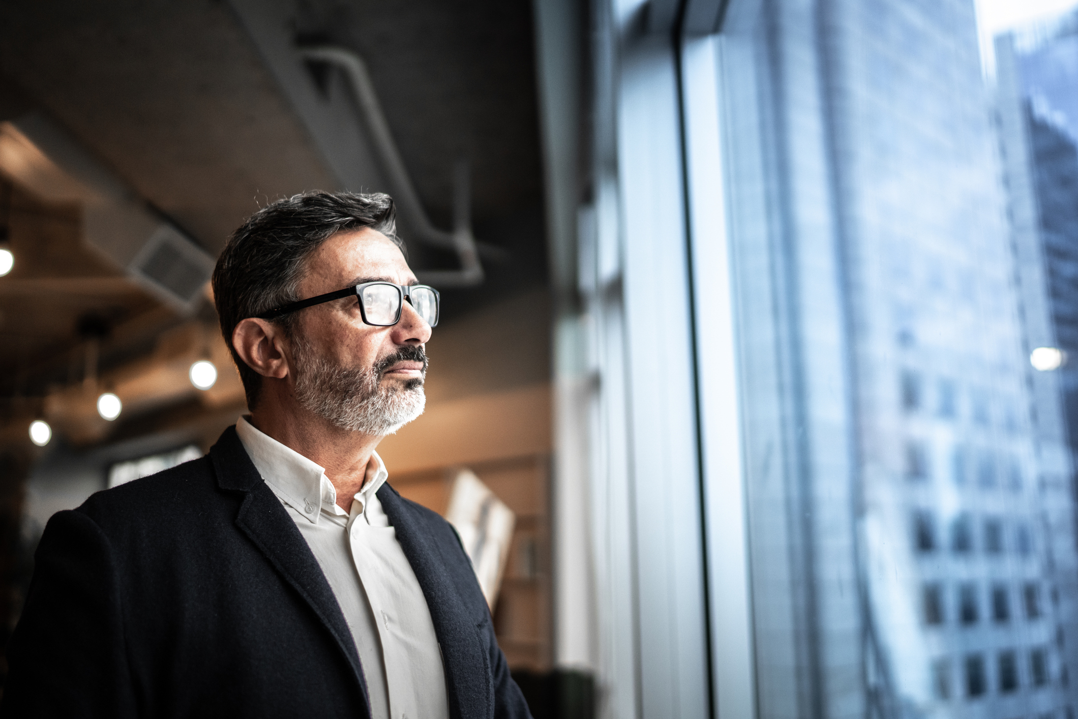 Älterer Geschäftsmann schaut aus dem Fenster iStock-1326254031