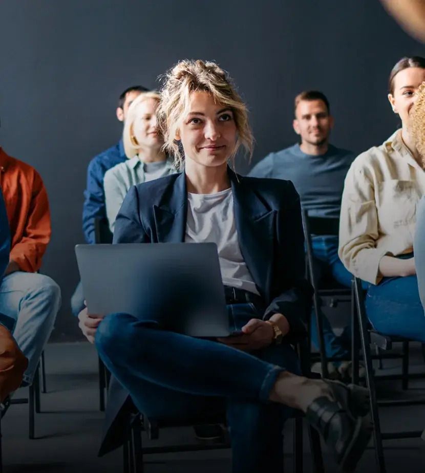 Glückliche Geschäftsleute, die auf einer Bildungsveranstaltung in ihrem Unternehmen sitzen iStock-1408517185 1